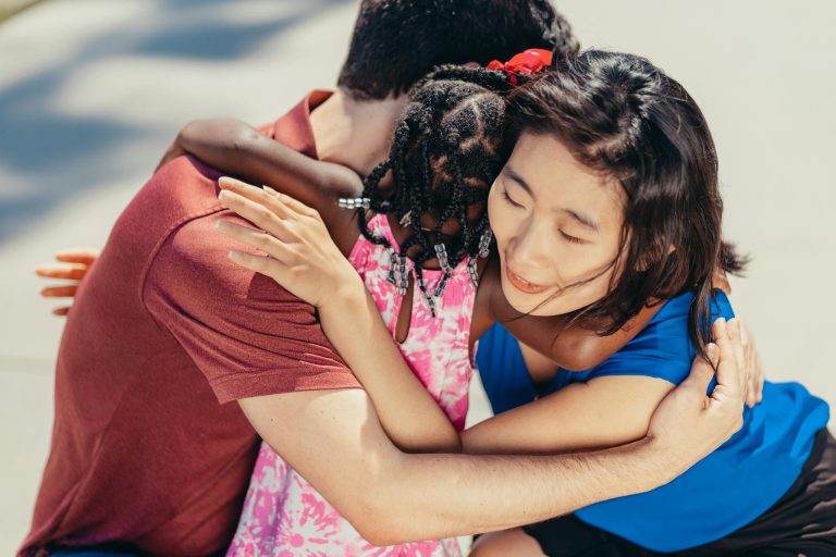 A diverse family shares a heartfelt hug outdoors, symbolizing love and unity.